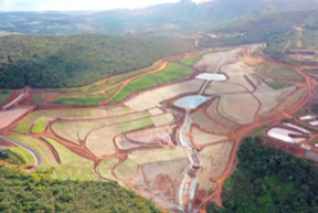 Vista aérea de uma barragem descaracterizada, mostrando uma vasta área com diversos níveis de terraços e pequenos lagos formados por água acumulada.
